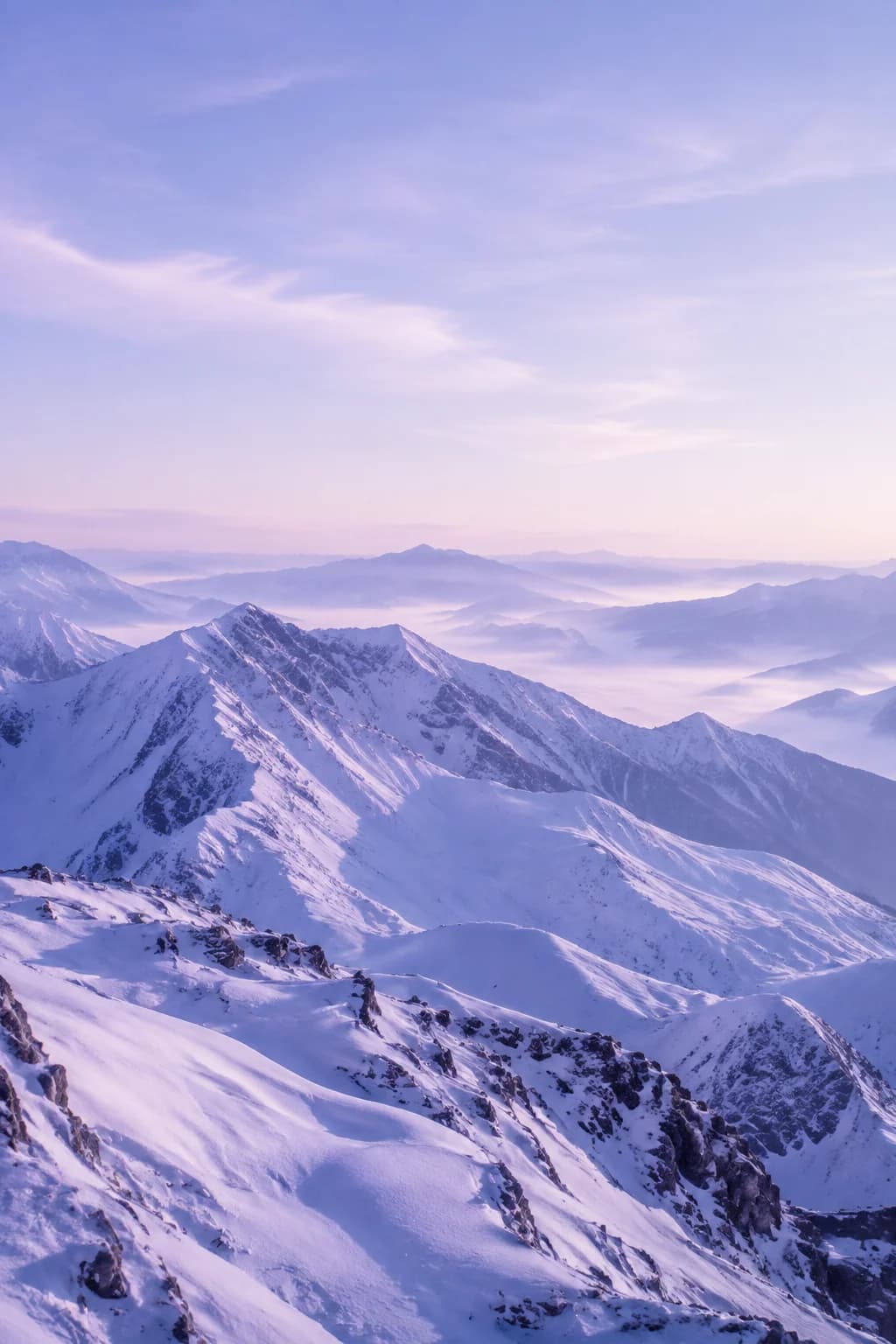 Snow-covered alpine peaks beneath a soft periwinkle sky